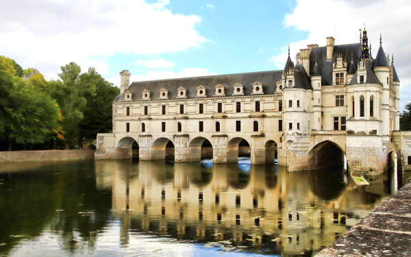 Stunning view of the Château de Chenonceau, reflecting beautifully on the water, surrounded by lush greenery, creating a captivating backdrop for any desktop wallpaper.
