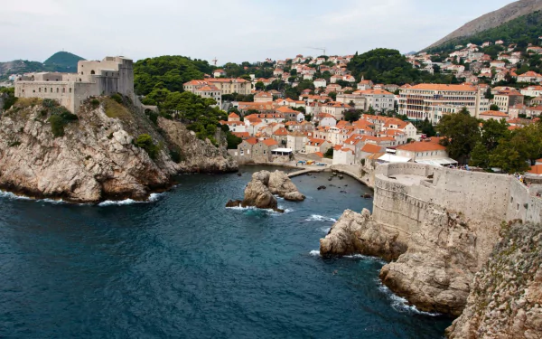 HD desktop wallpaper showcasing the man-made stone walls and buildings of Dubrovnik overlooking the blue Adriatic Sea.