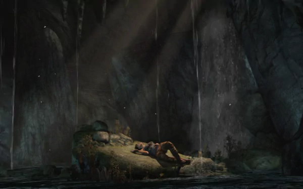 HD PC desktop wallpaper: Lara Croft from Tomb Raider (2013) rests on a rocky bank inside a dim cave, shafts of light and dripping water framing the atmospheric video game scene.