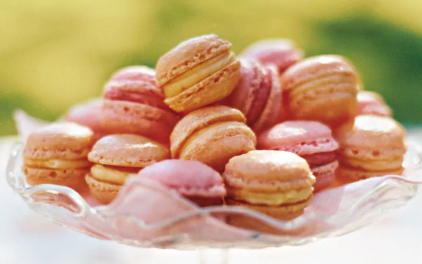 HD desktop wallpaper of colorful macarons stacked on a glass dish, showcasing the delicate texture and vibrant hues of the French pastry.