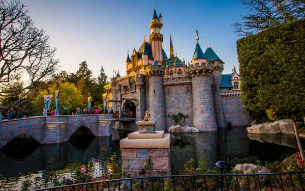 HD desktop wallpaper of Disneyland's iconic castle, captured in beautiful light with reflections on the surrounding moat.