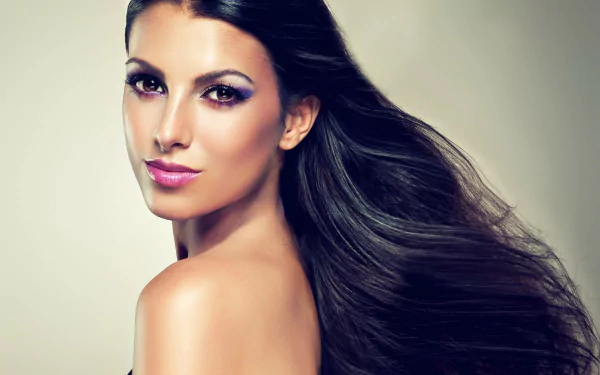 A woman with long, flowing hair gazes over her shoulder, showcasing a radiant look. This stunning image serves as a captivating HD desktop wallpaper and background.