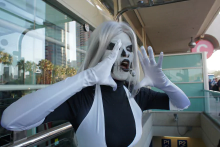 HD PC desktop wallpaper and background of a woman in monochrome cosplay with white face paint and silver hair, wearing long gloves and striking a dramatic pose on an outdoor balcony.