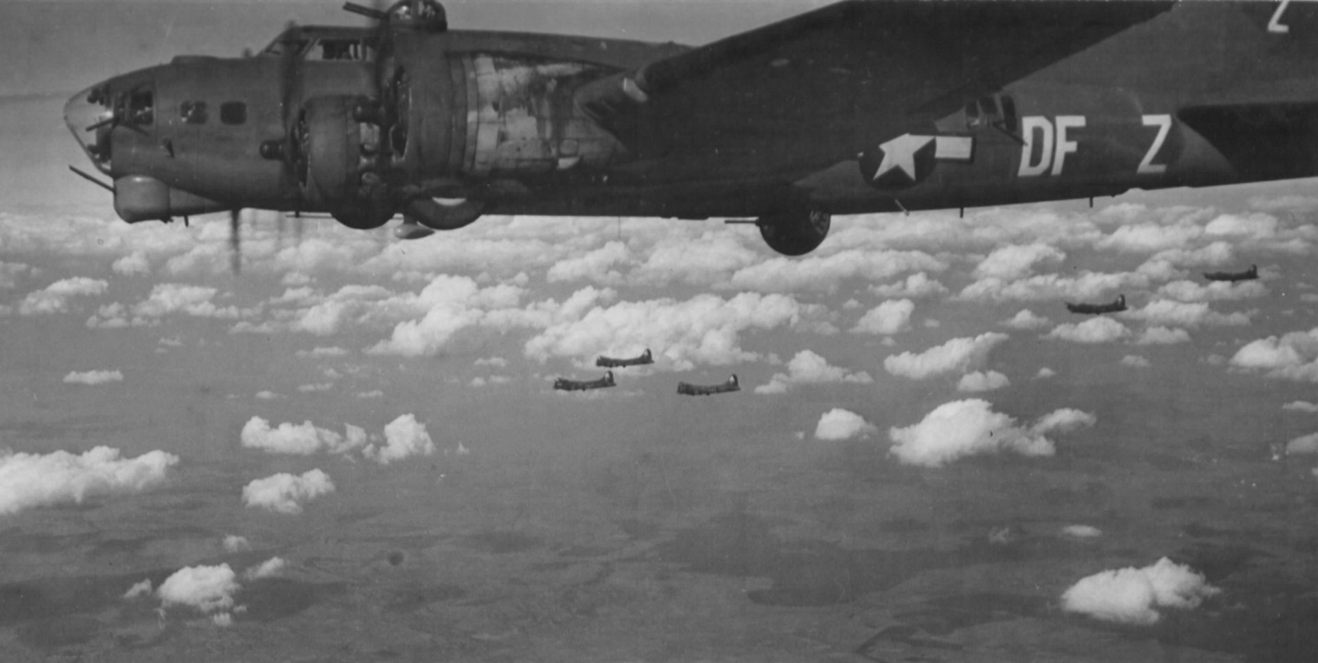 Grayscale aerial view of military Boeing B-17 Flying Fortress bombers in formation over clouds — 2K Quad HD PC desktop wallpaper and background.