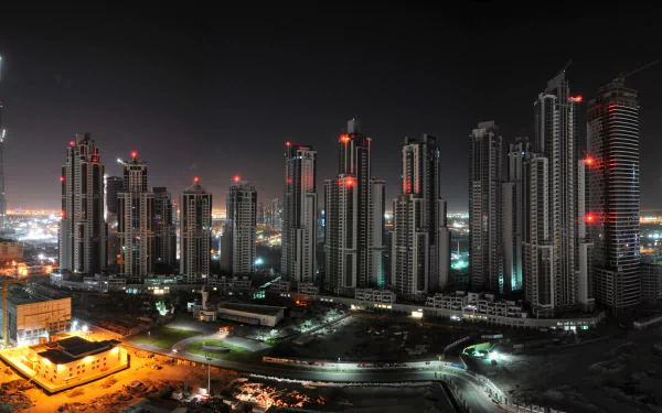 4K Ultra HD wallpaper of Dubai’s illuminated man-made skyline at night, showcasing towering skyscrapers with glowing red lights against a dark sky.