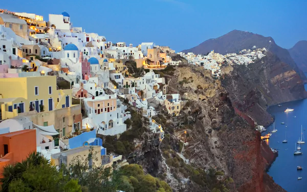 A stunning HD wallpaper featuring the iconic man-made architecture of Santorini, showcasing colorful buildings perched along a cliffside with a serene sea view.