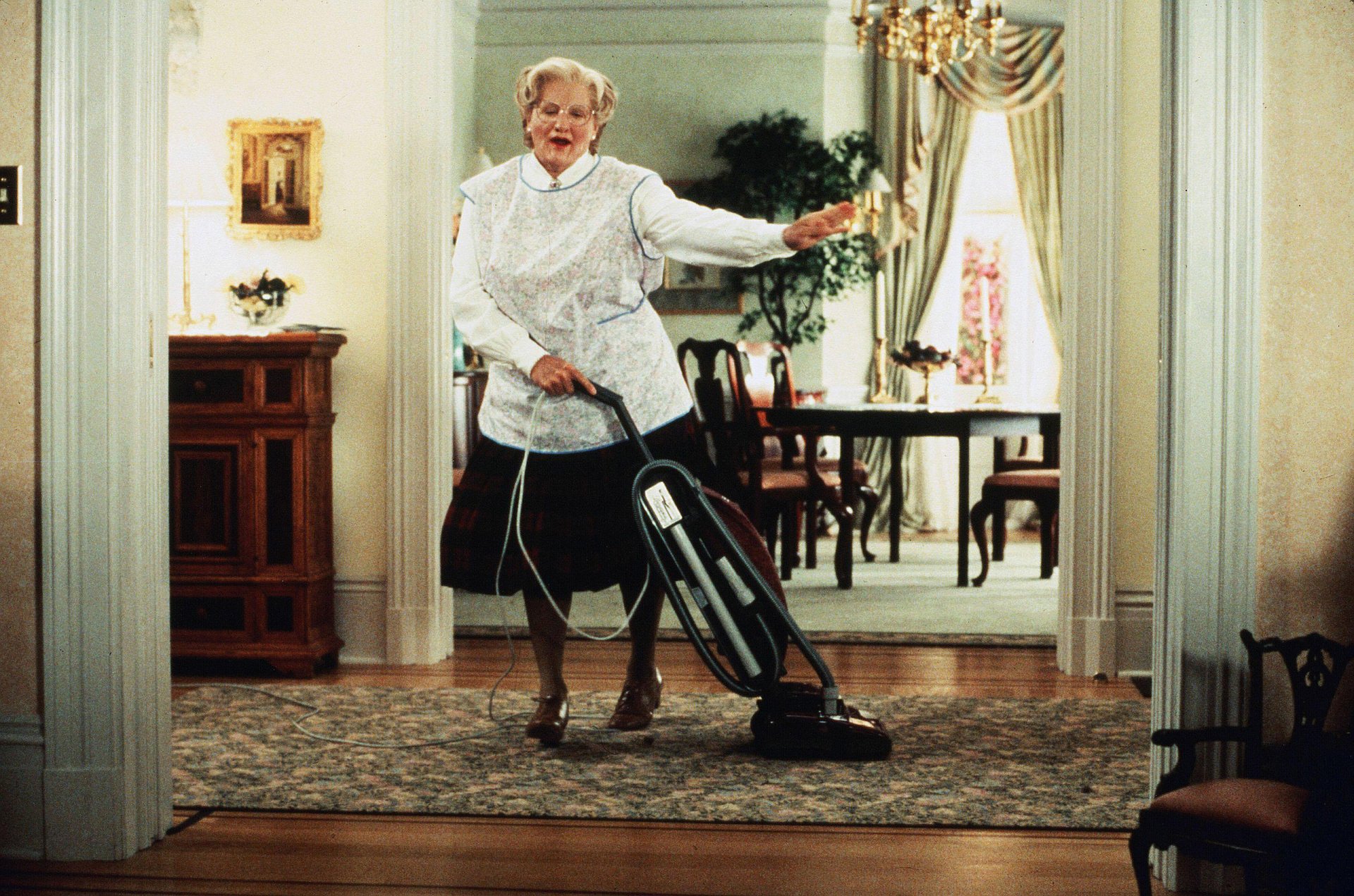 HD desktop wallpaper of Mrs. Doubtfire dancing with a vacuum cleaner in a well-furnished room.