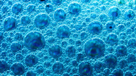 Macro photography of layered blue soap bubbles and foam creating a textured, iridescent pattern — vibrant HD PC desktop wallpaper and background.