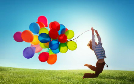 A joyful person jumps in a green field, holding a cluster of colorful balloons. The bright blue sky enhances this vibrant scene, making it a lively HD desktop wallpaper and background.