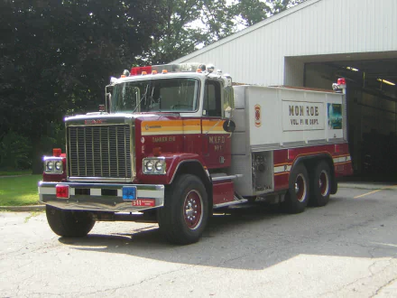 HD PC desktop wallpaper showing a red-and-white GMC General fire/rescue truck parked outside a garage building.