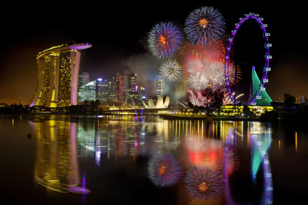 HD PC desktop wallpaper featuring vibrant fireworks lighting up the night sky over a city skyline with reflections in the water, captured in stunning photography.