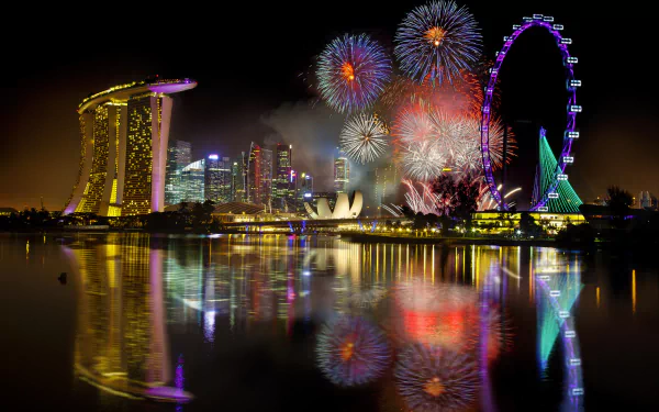 HD PC desktop wallpaper featuring vibrant fireworks lighting up the night sky over a city skyline with reflections in the water, captured in stunning photography.