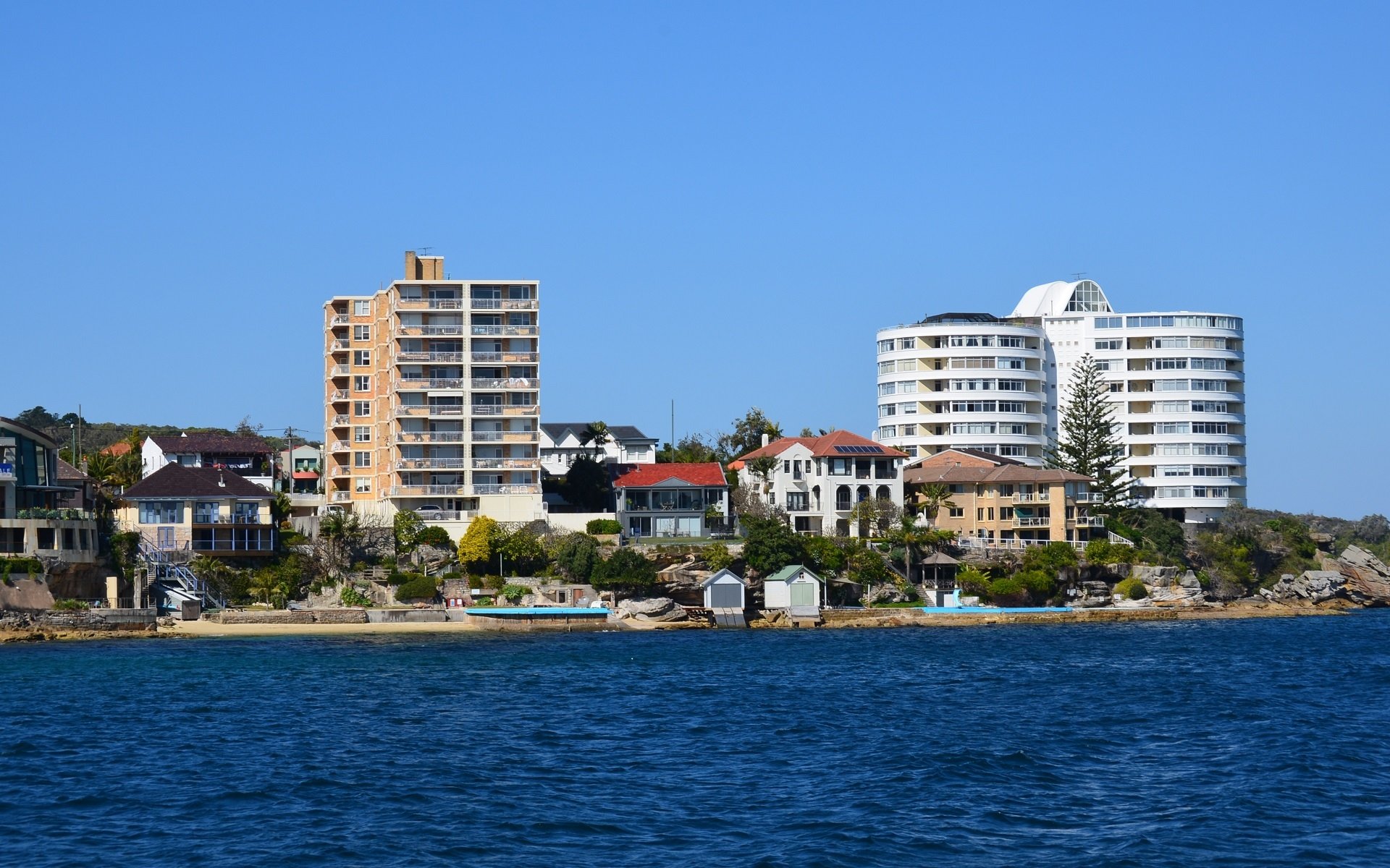 HD PC desktop wallpaper showing Sydney coast with man-made buildings and a manly waterfront skyline beneath a clear blue sky.
