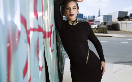 HD PC desktop wallpaper of a female singer in a black dress leaning against a graffiti-covered wall on a city rooftop, striking a confident pose with an urban music vibe.