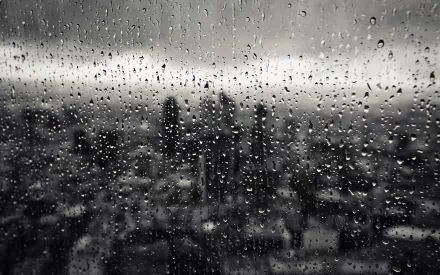 HD desktop wallpaper featuring a monochrome image of raindrops on a glass window with a blurred cityscape background.