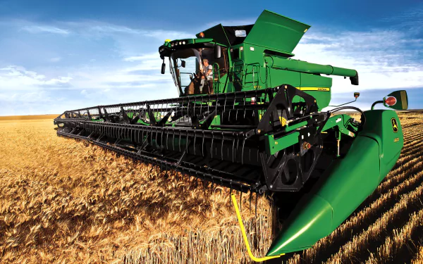 An HD desktop wallpaper features a John Deere combine harvester in action, cutting through golden fields under a clear blue sky, showcasing agricultural machinery in vibrant detail.