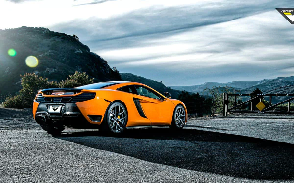 Orange McLaren sports car on a scenic mountain road under a dramatic sky — HD PC desktop wallpaper/background.