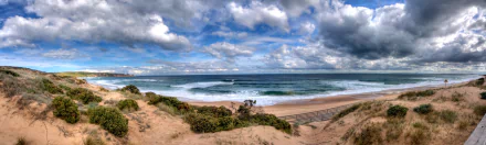 HD desktop wallpaper showing the natural beauty of Phillip Island with sandy dunes, ocean waves, and a dramatic cloudy sky on a scenic island coastline.