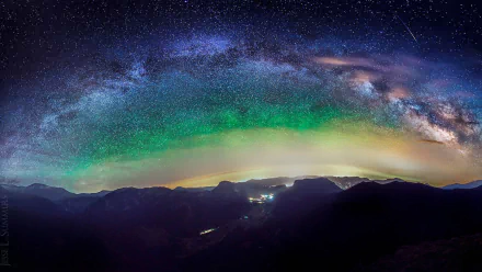 A stunning HD PC desktop wallpaper featuring an expansive night sky filled with stars and a vibrant Milky Way, set against a mountainous landscape.
