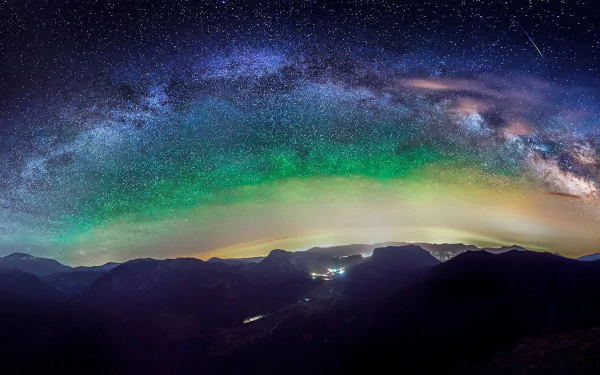 A stunning HD PC desktop wallpaper featuring an expansive night sky filled with stars and a vibrant Milky Way, set against a mountainous landscape.