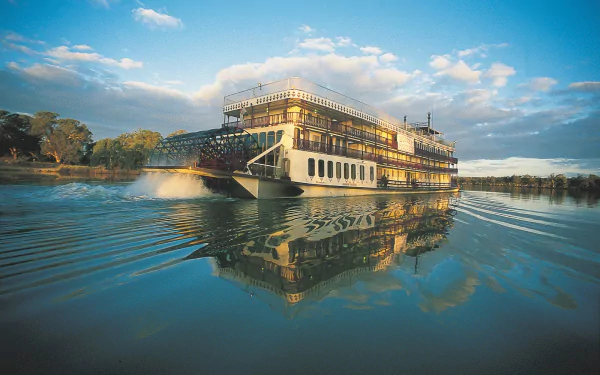 Paddle steamer boat gliding across a calm river at sunrise, mirrored in the water, a river vehicle — HD PC desktop wallpaper and background.