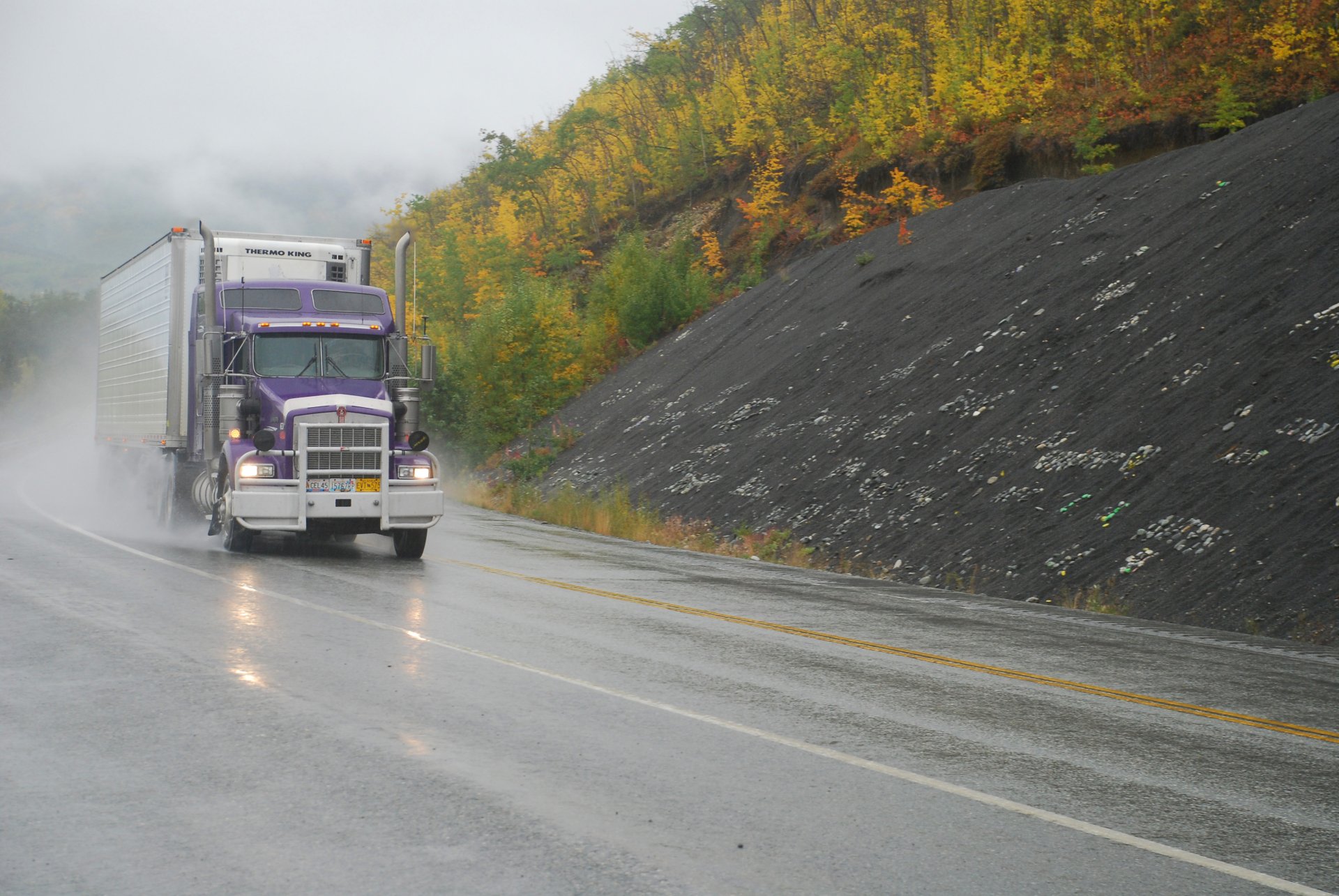 4K Ultra HD PC desktop wallpaper and background: purple Kenworth vehicle hauling a trailer on a wet highway, autumn foliage along the misty roadside.