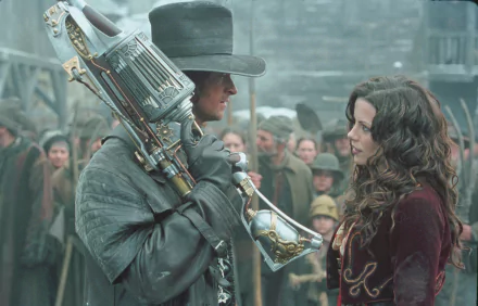 A dramatic scene from Van Helsing, featuring Hugh Jackman as the hunter and Kate Beckinsale as Anna Valerious, set against a backdrop of onlookers in a snowy village. HD wallpaper.