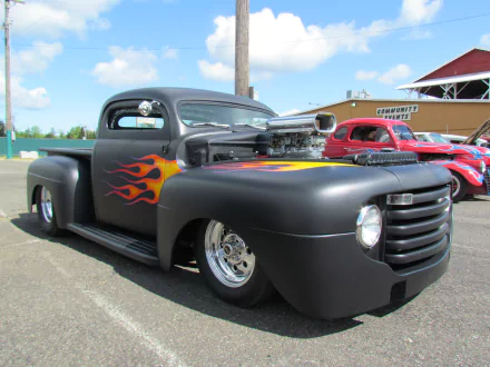 Vintage Ford truck with matte black paint and flame decals, showcased in a clear outdoor setting, captured in 4K Ultra HD for PC desktop wallpaper use.