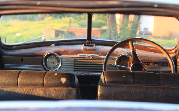 4K Ultra HD PC desktop wallpaper: close-up of a vintage car interior, wooden dashboard and steering wheel bathed in warm light.