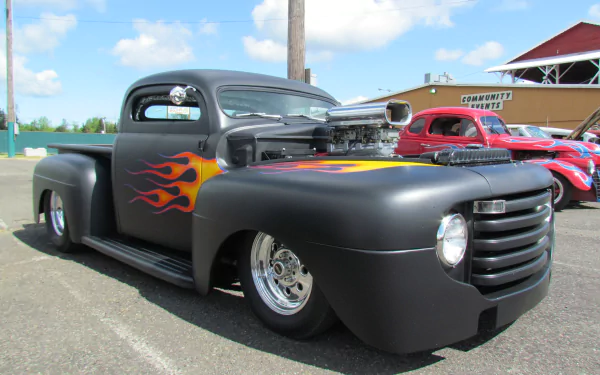 Vintage Ford truck with matte black paint and flame decals, showcased in a clear outdoor setting, captured in 4K Ultra HD for PC desktop wallpaper use.