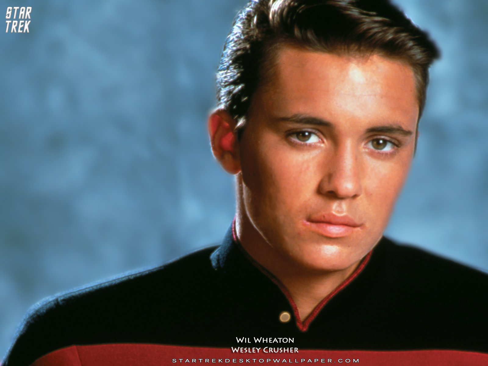 HD desktop wallpaper featuring a portrait of a young man with a dark shirt against a blue background.