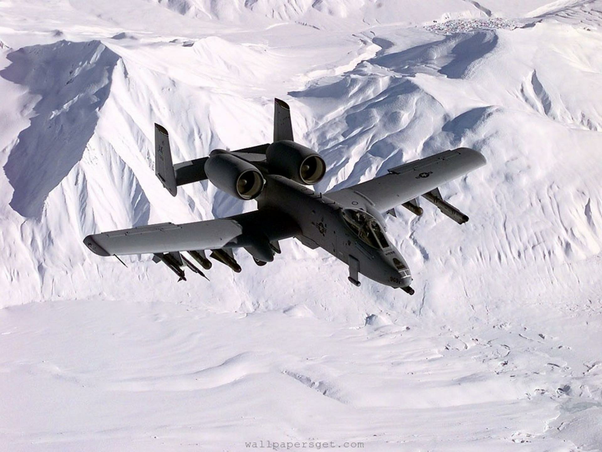 HD desktop wallpaper featuring a Fairchild Republic A-10 Thunderbolt II flying over snow-covered mountains in a military-themed scene.