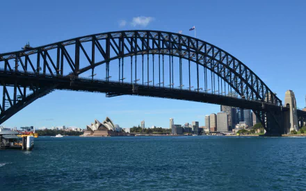 View of Sydney Harbour Bridge and Sydney Opera House with city skyline and harbor under clear blue sky in Australia.