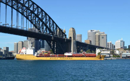 Yellow Stolt Tankers vessel and barge (boat/vehicle) passing beneath Sydney Harbour Bridge with city skyline and blue water — HD desktop wallpaper.