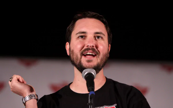 HD desktop wallpaper featuring a man with a microphone, smiling against a blurred background.