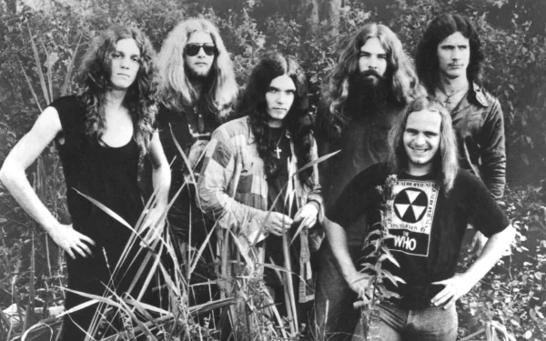 Black and white HD desktop wallpaper featuring the rock band Lynyrd Skynyrd standing outdoors among tall grass, capturing their classic music era style.