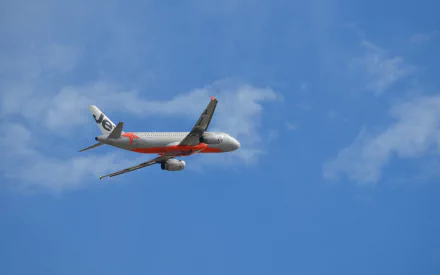 An Airbus A320 aircraft from Jetstar soars through a clear blue sky, showcasing its sleek design and vibrant colors. HD wallpaper depicting aviation themes.