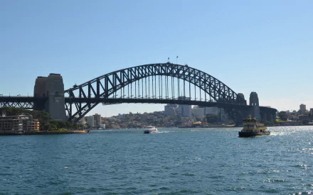 HD desktop wallpaper featuring a ferry crossing Sydney Harbour with the iconic Sydney Harbour Bridge and city skyline in the background under a clear blue sky.