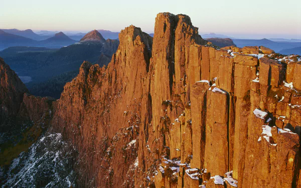 HD desktop wallpaper showcasing Cradle Mountain's rugged peaks bathed in warm sunlight, surrounded by expansive natural wilderness.