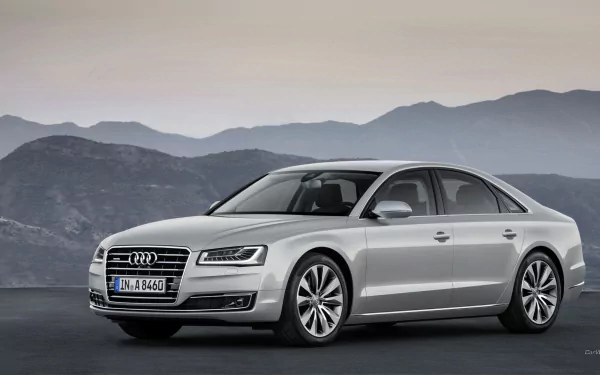 A sleek silver Audi A8 stands prominently against a mountainous backdrop, showcasing its elegant design in this HD desktop wallpaper and background.