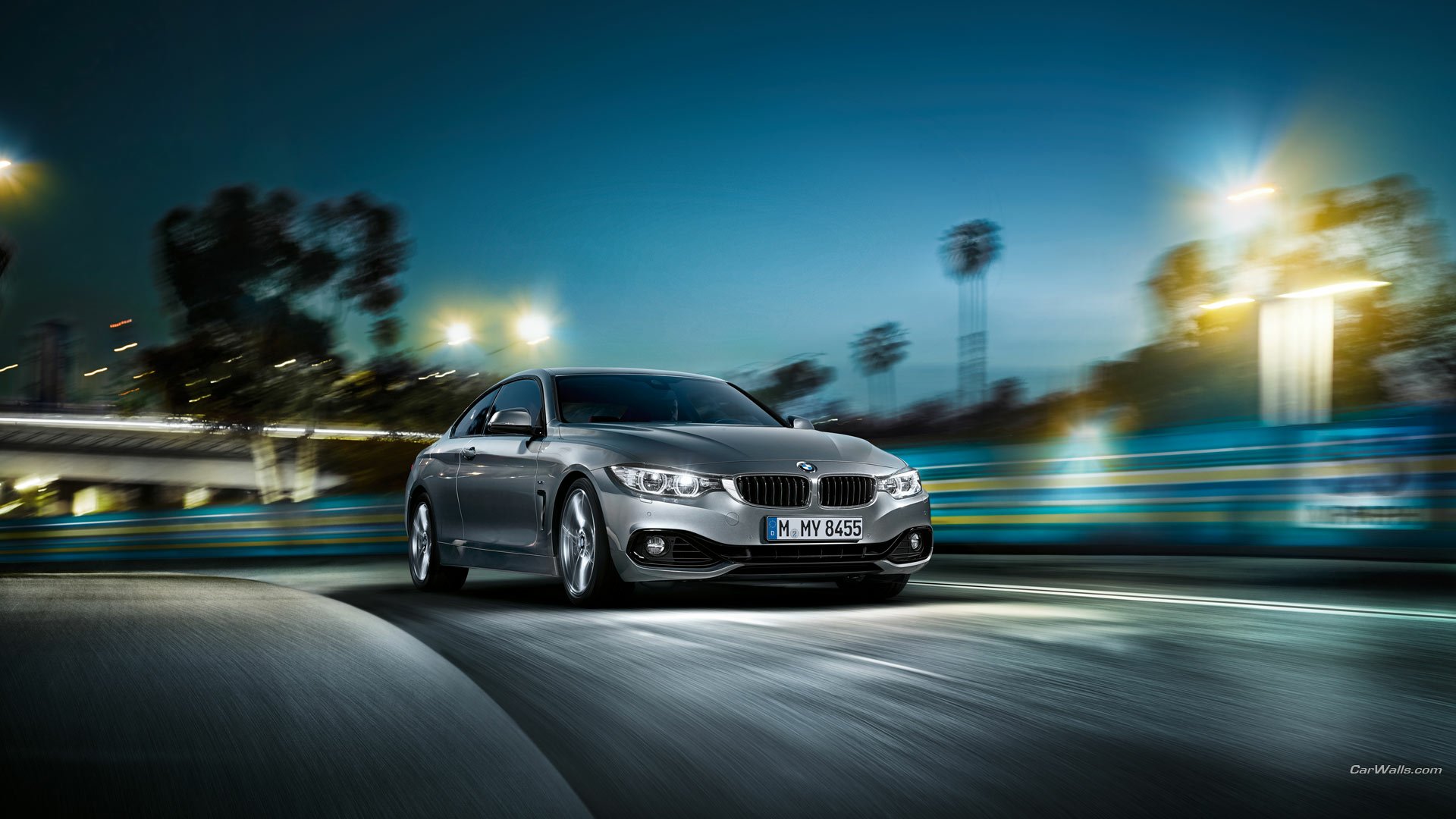 Silver BMW 4 Series Coupe vehicle speeding through lit city streets at night, motion-blurred HD PC desktop wallpaper/background.