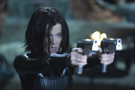 HD PC desktop wallpaper featuring a scene from the movie Underworld: Awakening, showing a fierce woman with glowing blue eyes aiming dual pistols.