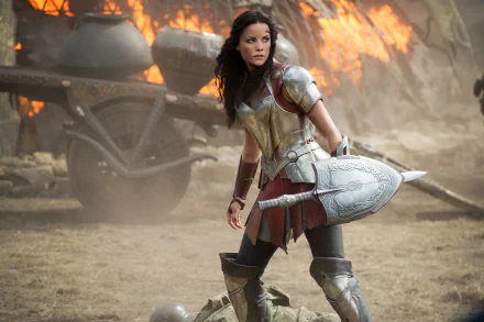 HD PC desktop wallpaper featuring a scene from the movie Thor: The Dark World, showcasing a fierce female warrior in armor amid a fiery battlefield.