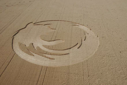 HD desktop wallpaper featuring a detailed man-made crop circle design in a vast golden field.