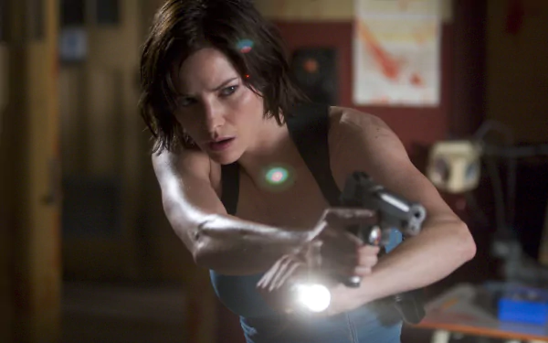 2K Quad HD desktop wallpaper: tense still from Resident Evil: Apocalypse — a female protagonist aims a handgun with a flashlight in a dim, cluttered interior.