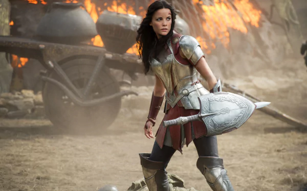 HD PC desktop wallpaper featuring a scene from the movie Thor: The Dark World, showcasing a fierce female warrior in armor amid a fiery battlefield.