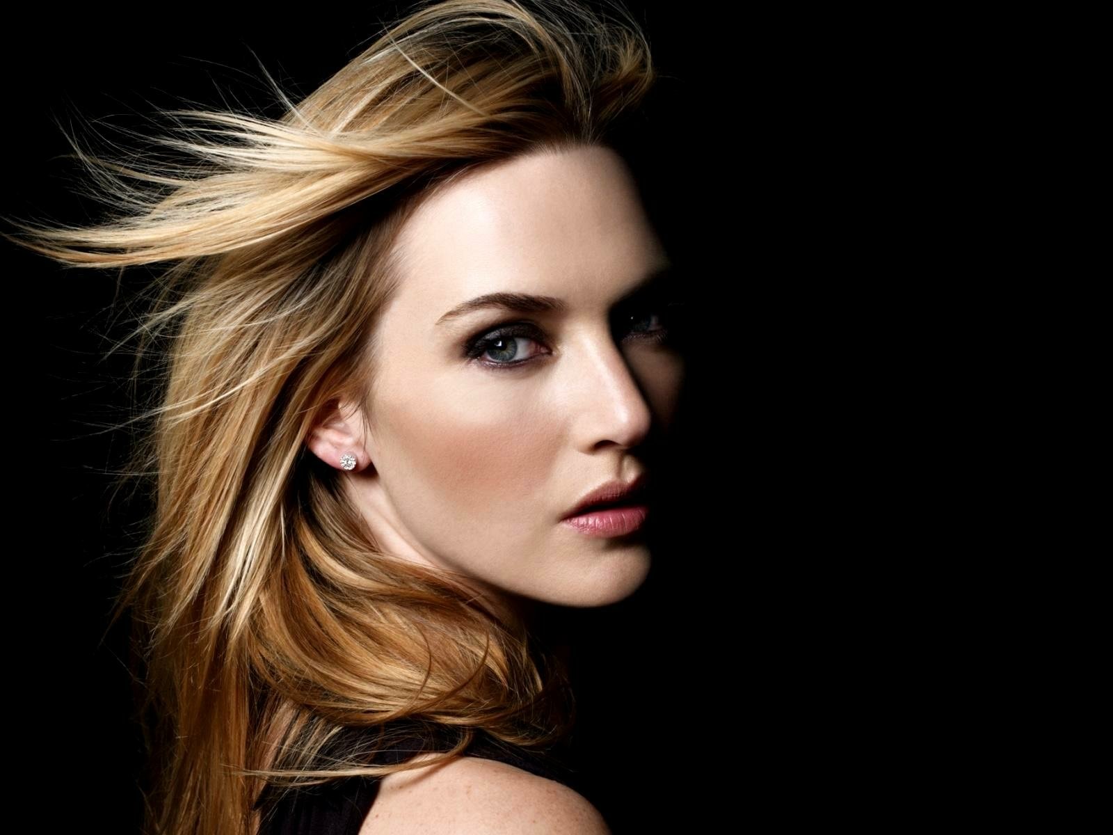 HD PC desktop wallpaper featuring a close-up portrait of celebrity Kate Winslet with flowing blonde hair against a dark background.