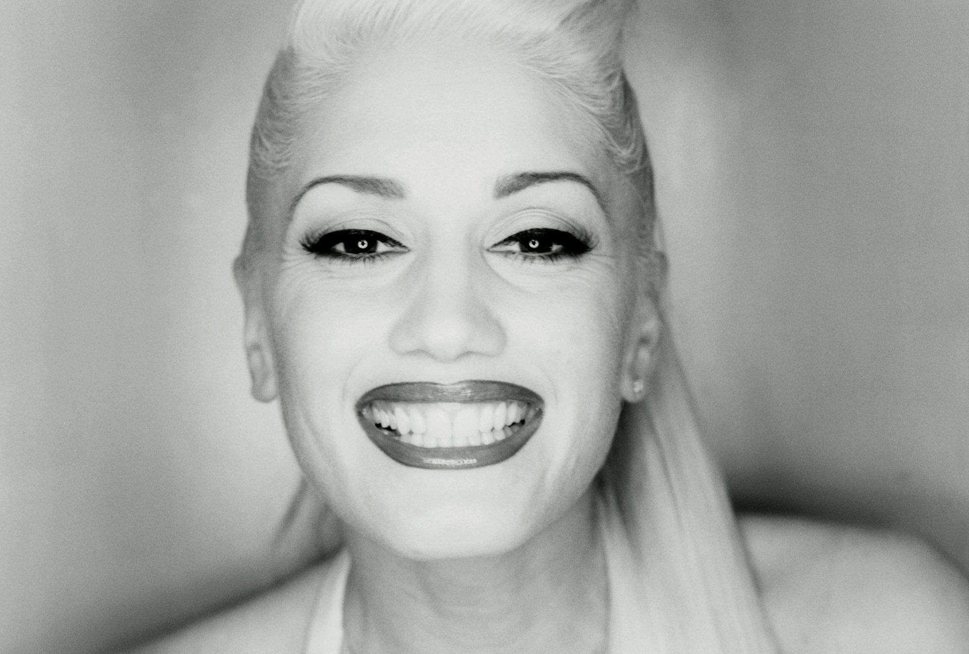 Black and white HD desktop wallpaper featuring a close-up of Gwen Stefani smiling, highlighting her iconic style and music influence.