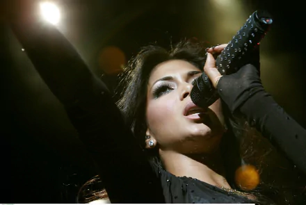 HD PC desktop wallpaper featuring Nicole Scherzinger passionately singing into a microphone, capturing the energy of a live music performance.