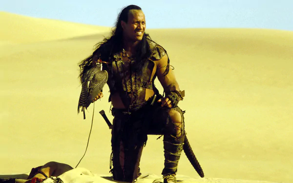 Armored warrior kneels on sunlit desert dunes clutching a hawk and scimitar — cinematic still from The Scorpion King, 2K Quad HD PC desktop wallpaper